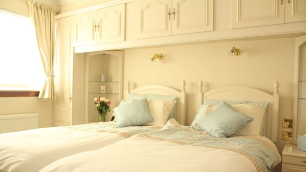 A double bed with a white headboard and two pillows, a nightstand with a lamp, and a window with curtains. - Abbot`s House in Doonfoot (Doonfoot)