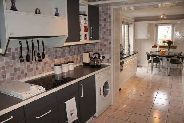 A modern kitchen with a built-in washing machine, a coffee maker, and a kettle on the countertop.