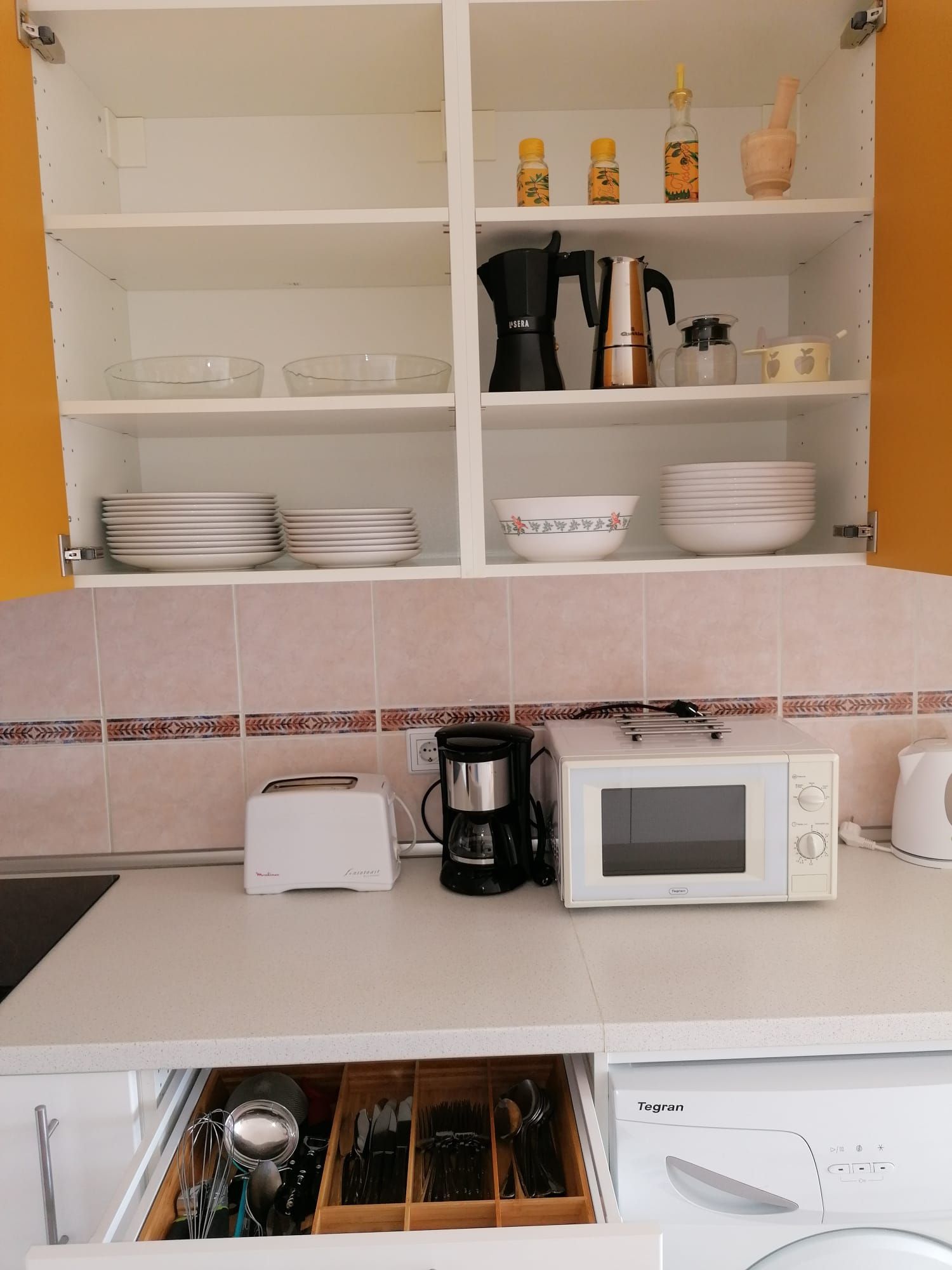 A kitchen with white cabinets, a microwave, a toaster, and a coffee maker.