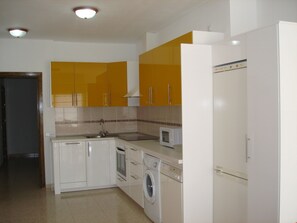 A kitchen with white cabinets, a microwave, a washing machine, and a refrigerator.