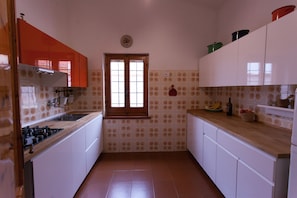 A kitchen with white cabinets, a wooden countertop, and a window with a view. - Villa Paolina: private pool, large shady patio, front garden. (Calasetta)