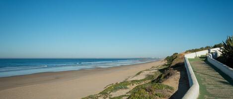A coastal road with a sandy beach and a clear blue sky.