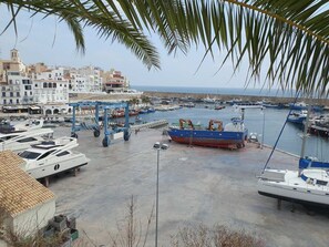 Un puerto deportivo con barcos amarrados, vista despejada al mar y edificios al fondo.