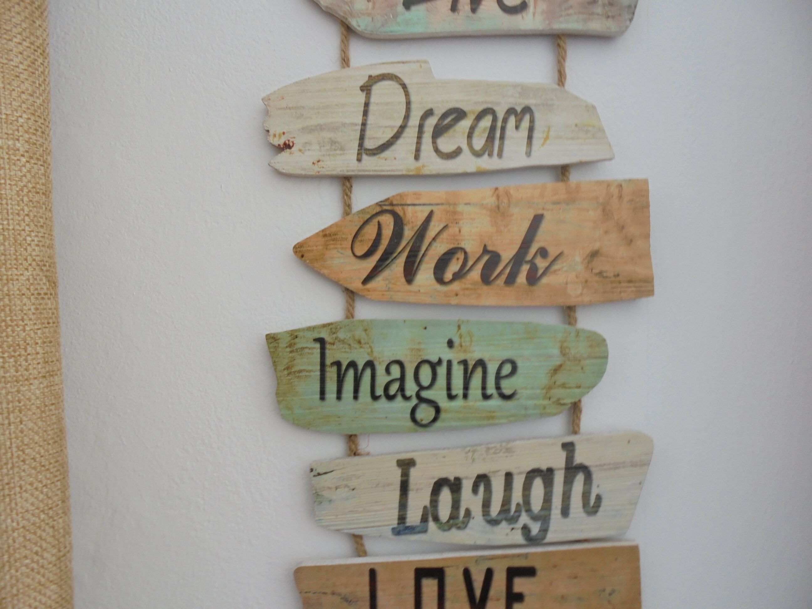 A wall with wooden signs that read "Dream," "Work," "Imagine," "Laugh," and "Love."