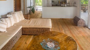 Ein großzügiger Wohnbereich mit einer Couch, einem Couchtisch mit einer Glasbowl und einer Küche im Hintergrund.