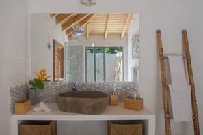 Un baño con un espejo grande, un lavabo de piedra y un techo de madera.