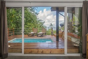 Zona junto a la piscina con dos sillones de descanso, una parrilla y vistas al océano.
