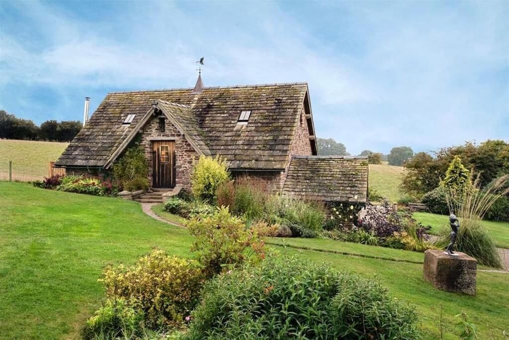 A rustic stone house with a sloped roof, a wooden door, and a small porch.