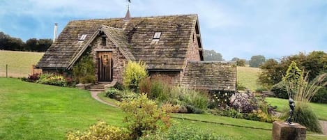 A rustic stone house with a sloped roof, a wooden door, and a small porch.