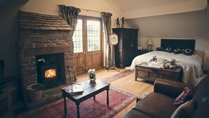 A cozy room with a stone fireplace, a bed with decorative headboard, and a wooden chest. - The Coach House is a retreat from the outside world. (Tenbury Wells)