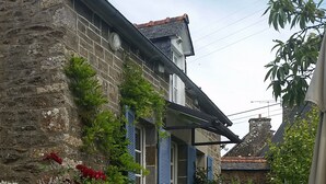 A stone building with a staircase leading to a door, surrounded by greenery and flowers. - Peaceful rural retreat  (Saint-Hélen)