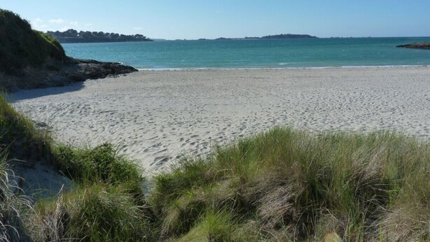 A beach with a clear sky, sandy shore, and grassy dunes. - Peaceful rural retreat  (Saint-Hélen)