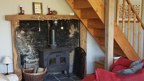 A cozy living room with a fireplace, wooden staircase, and a red sofa. - Peaceful rural retreat  (Saint-Hélen)
