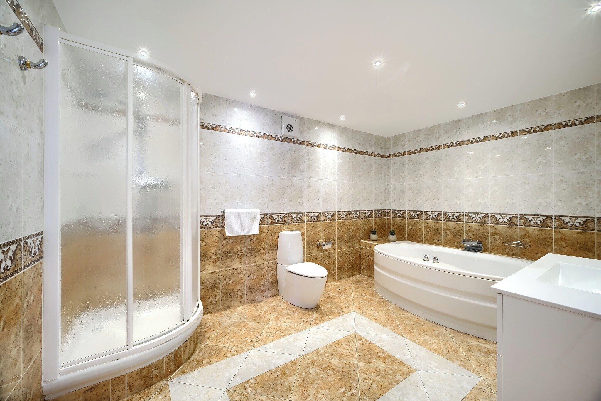 A bathroom with a glass shower enclosure, a bathtub, a toilet, and a sink.