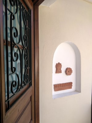 A window with ornate metal bars and a small decorative alcove with a flower and a brick-like object.