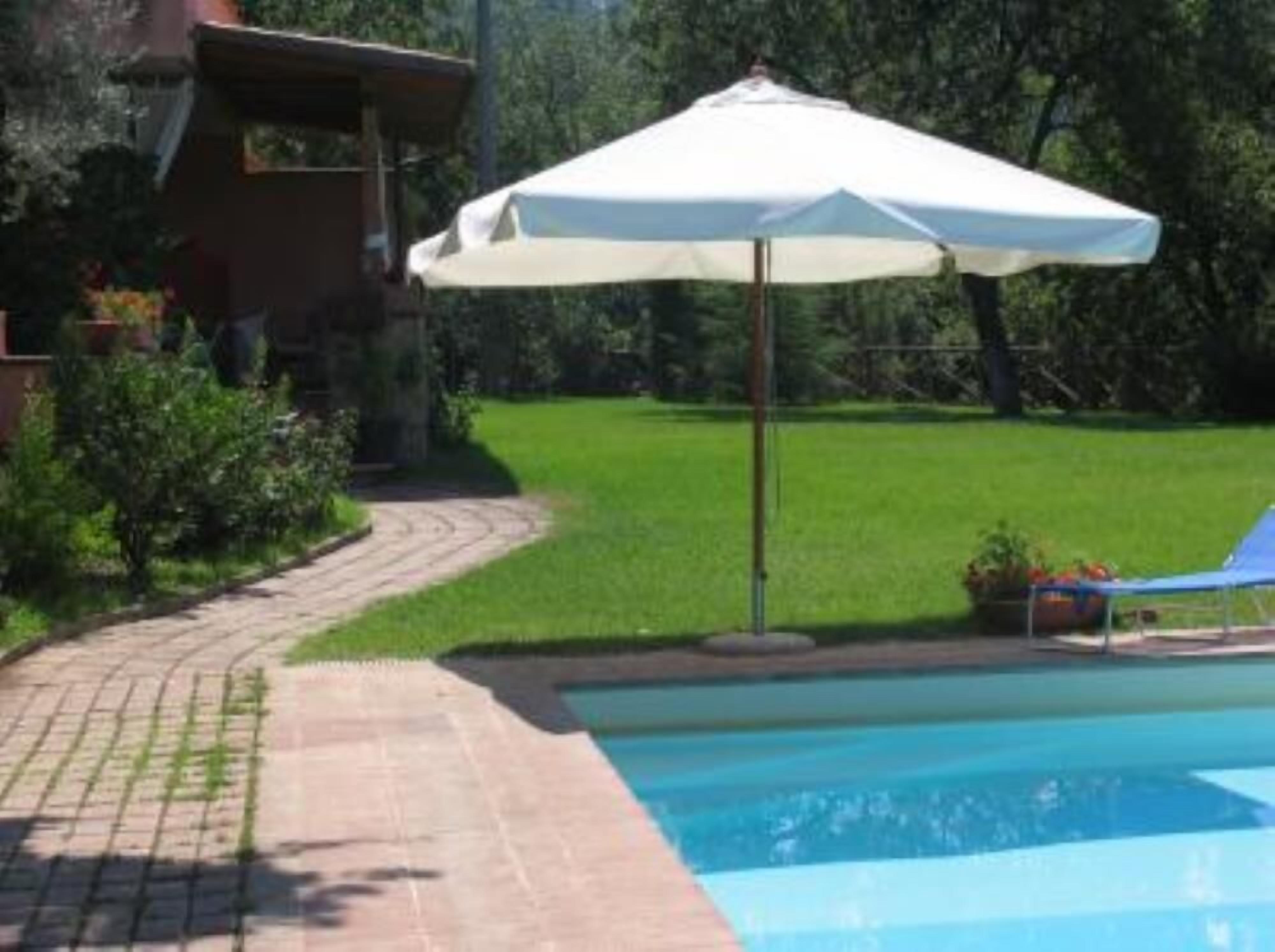 Une piscine avec une terrasse carrelée, un parasol blanc et un fauteuil de relaxation.