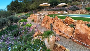 Un jardin aménagé avec une piscine, un espace salon extérieur et un mur en pierre.