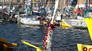 Un puerto deportivo con varios veleros amarrados, con distintas banderas y estandartes.