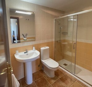 A bathroom with a sink, toilet, and glass-enclosed shower.