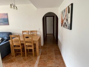 A dining area with a wooden table and chairs, a blue sofa, and a painting on the wall.