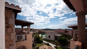 A residential area with stone and stucco buildings, a swimming pool, and a clear sky. - Nice apartment with roof terrace in an elegant complex with swimming pool (San Teodoro)