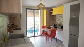 A modern kitchen with a dining area, a large window, and a built-in refrigerator. - Villa sea view heated pool 8 persons with electric charging point (Sainte Lucie de Porto Vecchio)