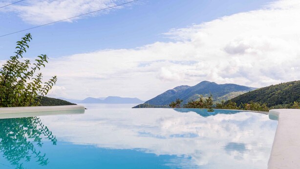 En vacker, turkosblå infinitypool med utsikt över berg och en klar himmel.
