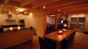 Una cocina acogedora con armarios de madera, una isla central con velas y un comedor con sillas.