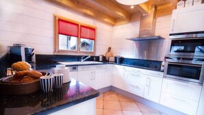 Una cocina moderna con armarios blancos, encimera negra y ventana con persianas rojas.