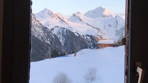 A view of snow-covered mountains through a window. - Apartment Harikoa, sleeps 5, next to piste, Col de Merdassier. (Manigod)