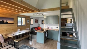 A modern interior with a dining area, kitchen, and a staircase. - Apartment Harikoa, sleeps 5, next to piste, Col de Merdassier. (Manigod)