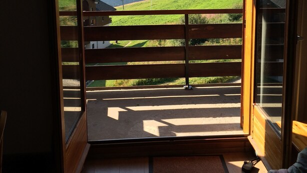 A room with a large sliding glass door leading to a balcony with a mountain view. - Apartment Harikoa, sleeps 5, next to piste, Col de Merdassier. (Manigod)