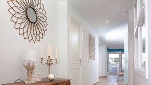 Un couloir avec une console en bois, un miroir fixé au mur et un lustre.