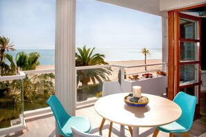 A balcony with a view of the beach, a round table with chairs, and a candle on the table. - LUXURIOUS PENTHOUSE ON THE BEACH (MODERN DESIGN) (Alcúdia)