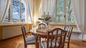 A dining area with a wooden table, chairs, a chessboard, and a vase of flowers.