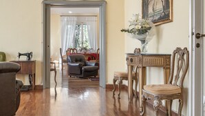 A room with a wooden floor, a sofa, a chair, a table, and a painting on the wall.