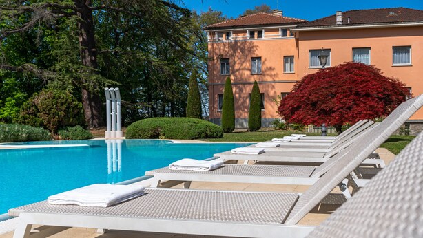 A swimming pool with lounge chairs and a building in the background.
