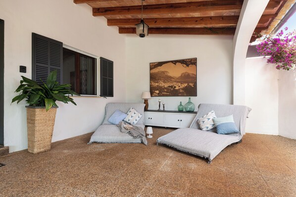 A cozy room with two grey sofas, a wooden ceiling, a large painting, and a potted plant.