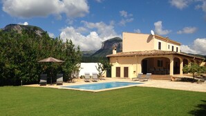 Eine Villa mit Swimmingpool, Sitzgelegenheit im Freien und Blick auf die Berge.