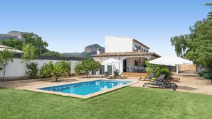 Ein Garten mit Swimmingpool, einer Terrasse und Gartenmöbeln sowie Blick auf ein Gebirge.