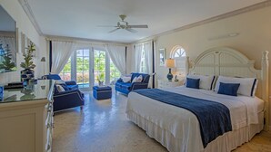 Un dormitorio amplio con una cama grande, una zona de estar con un sofá azul y vistas al exterior a través de amplios ventanales.