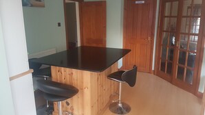 A kitchen with a wooden island, two bar stools, a refrigerator, and a door labeled "Private". - Spacious House, Just Five Minutes Walk From Beach, Perfect for Families/Surfers (Bude)