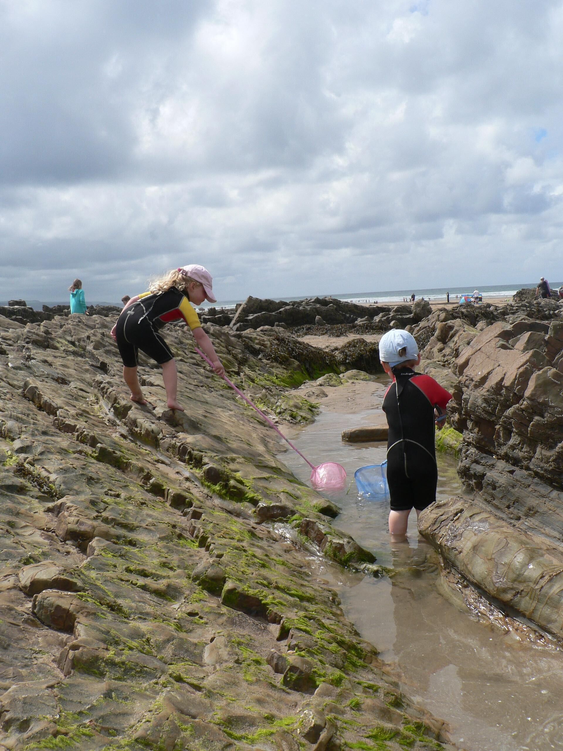 Une plage rocheuse où l’on peut voir des gens pratiquer des activités nautiques.