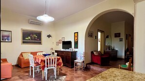 A dining area with a table set for two, a sofa, and a television.