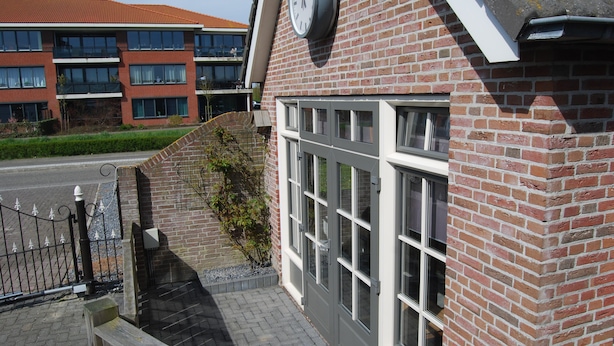 A brick building with large windows and a clock on the wall. - Detached holiday home in Westkapelle for 4 people. (Westkapelle)