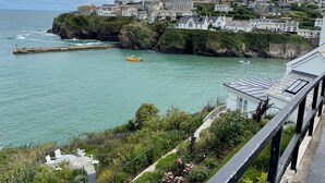 Un pueblo costero con un acantilado rocoso, un muelle y un bote amarillo.