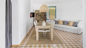 A dining area with a wooden table and chairs, a white sofa, and a bookshelf. - VACATION HOME 300 MT. BY THE SEA OF FINE GOLDEN SAND WITH PRIVATE POOL (Avola)
