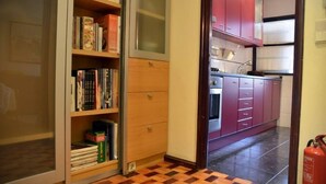 A hallway with a wooden floor, a bookshelf, and a kitchen area with red cabinets and a tiled backsplash. - Porto: OPorto Apartment Triplex (Porto)