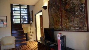 A staircase leading to a second floor, a television on a stand, and a large abstract painting on the wall. - Porto: OPorto Apartment Triplex (Porto)