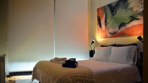 A bedroom with a large bed, a painting on the wall, and a nightstand with a lamp. - Porto: OPorto Apartment Triplex (Porto)